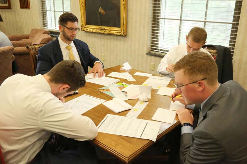a group of men sitting around a table with papers