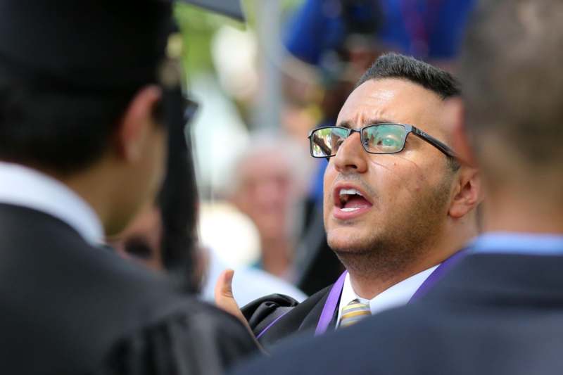 a man in a graduation gown talking to another man