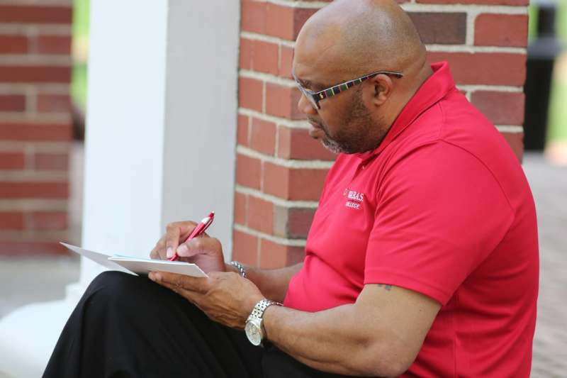 a man in a red shirt writing on a paper