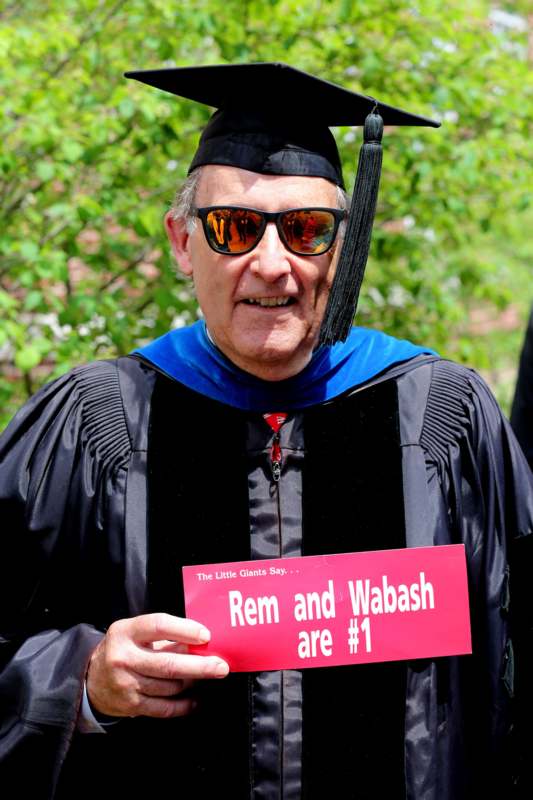 a man in a graduation gown holding a sign