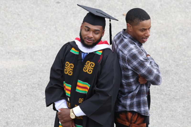 a man in a graduation gown and cap standing back to back