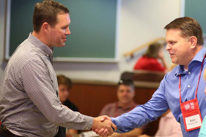 a man shaking hands with another man in a classroom
