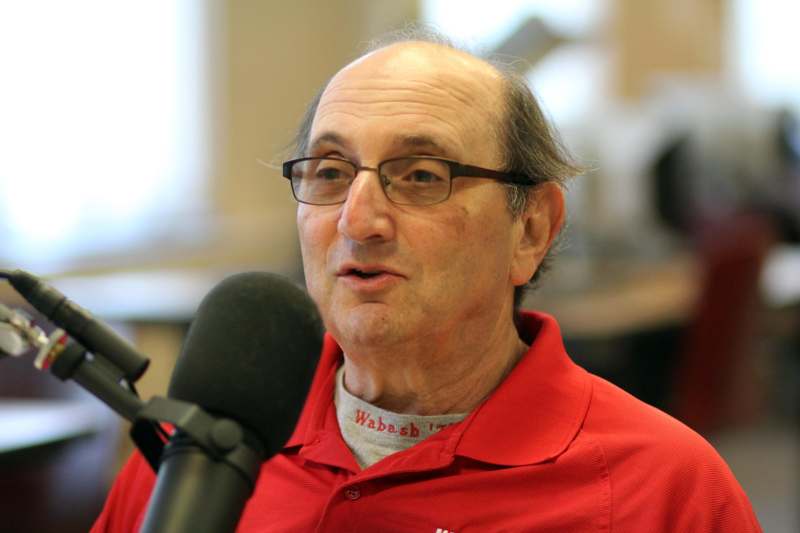 a man in a red shirt speaking into a microphone