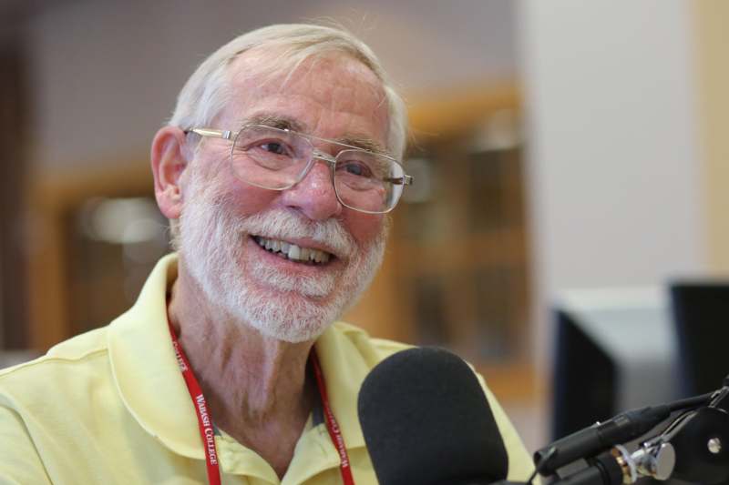 a man with glasses smiling at a microphone