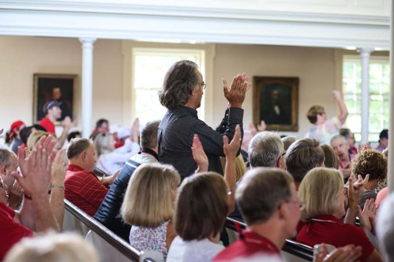 a man raising his hands in a room with people