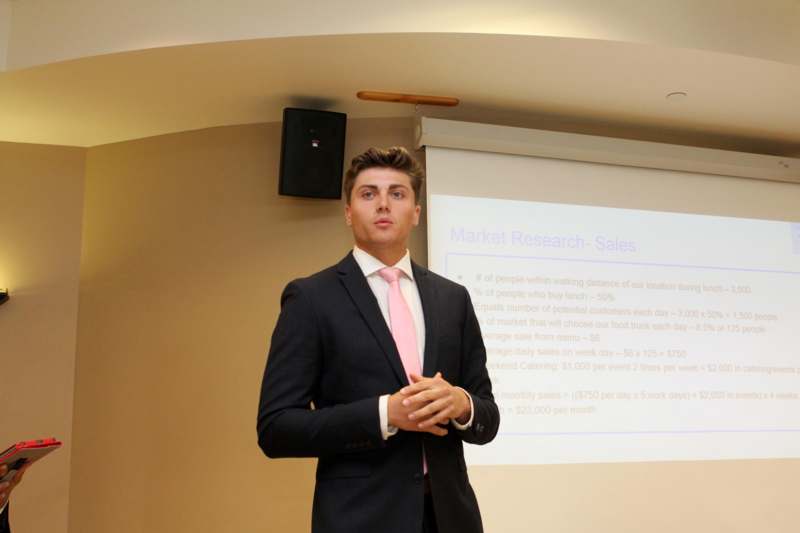 a man in a suit and tie standing in front of a projector screen