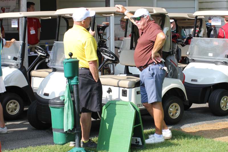 a group of men standing next to golf carts