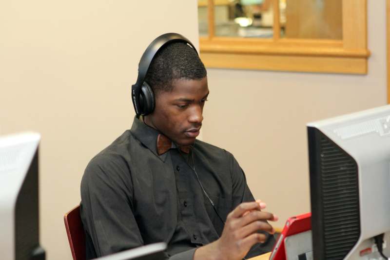 a man wearing headphones and looking at a red tablet