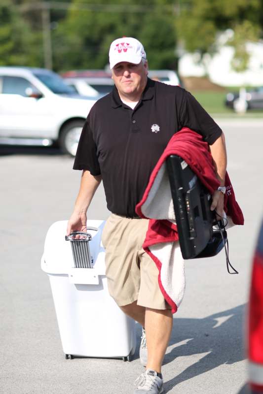 a man walking with a red blanket and a white cooler