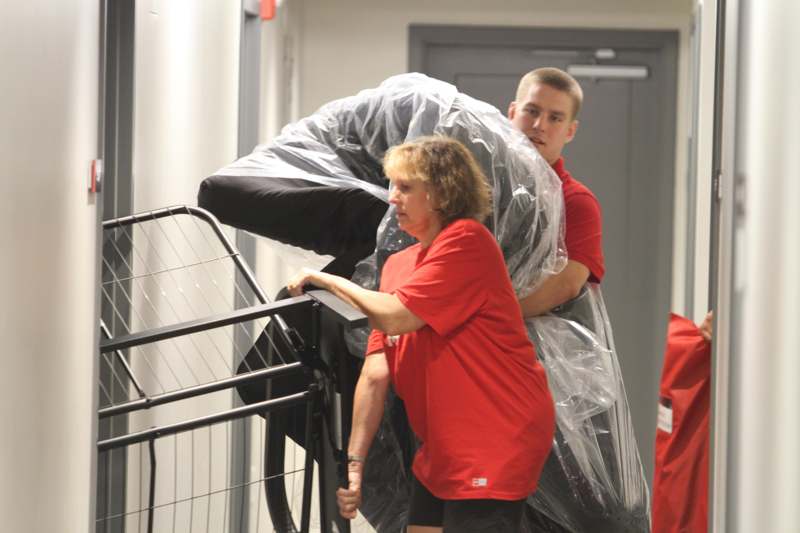 a man carrying a person in a plastic wrap