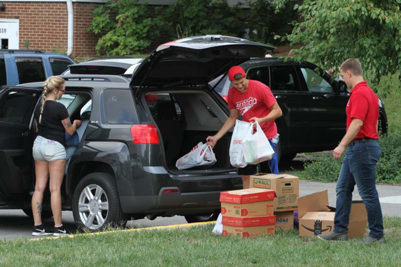 a group of people loading boxes into a car