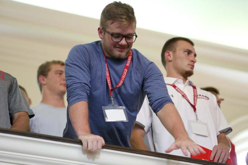 a man wearing lanyard and standing on a railing