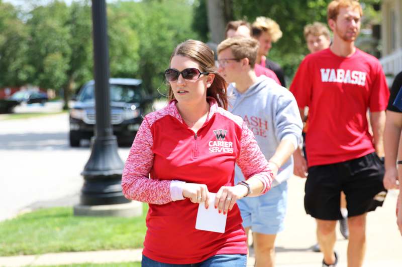 a woman in red shirt and sunglasses walking down a sidewalk