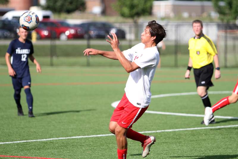 a man in a white shirt and red shorts running on a field