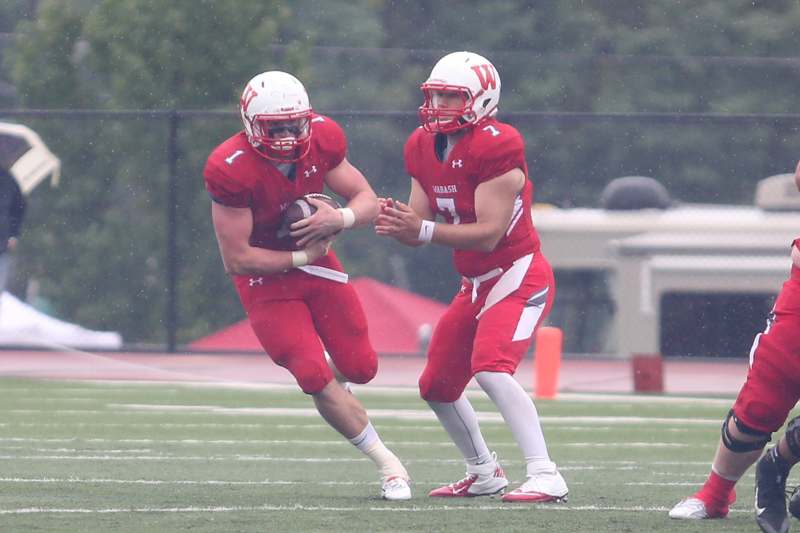 two football players in red uniforms holding a football