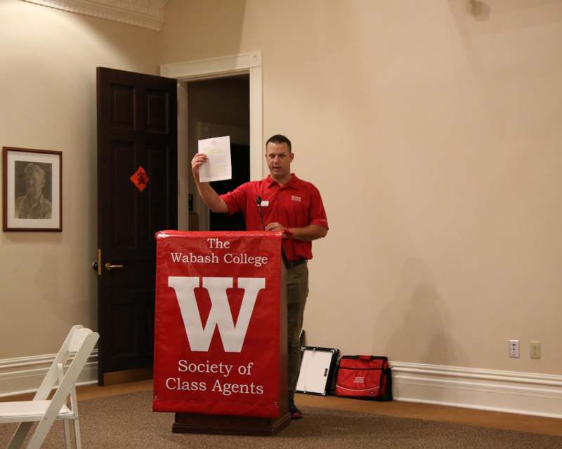 a man standing at a podium holding up a piece of paper