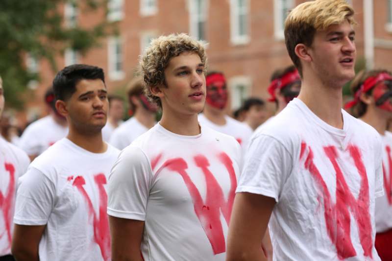 a group of men wearing white shirts with red paint on them