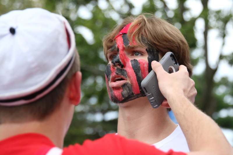 a man with a painted face talking on a cell phone