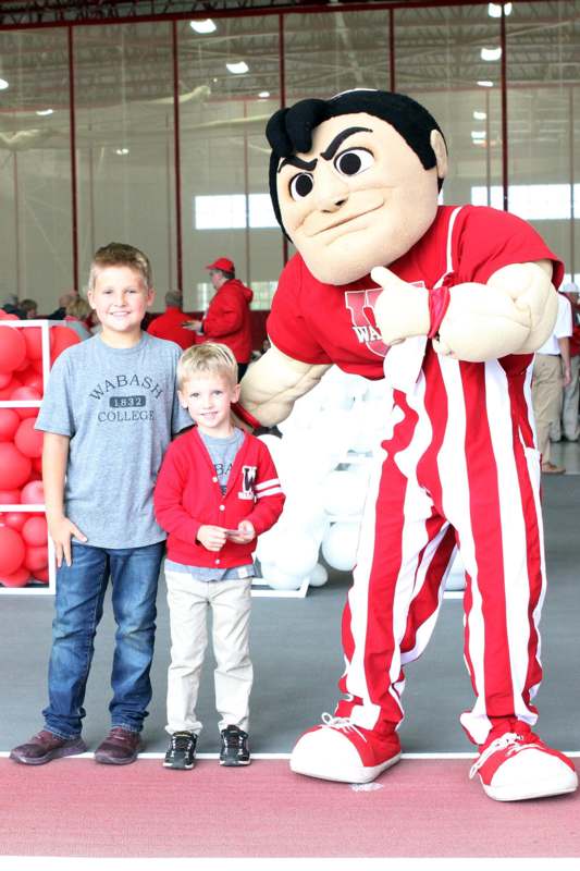 two boys posing with a mascot