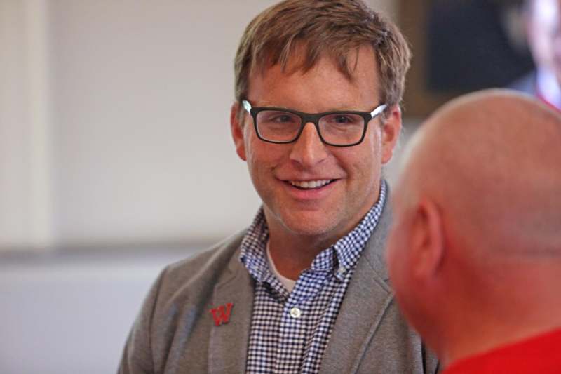 a man wearing glasses and a grey jacket