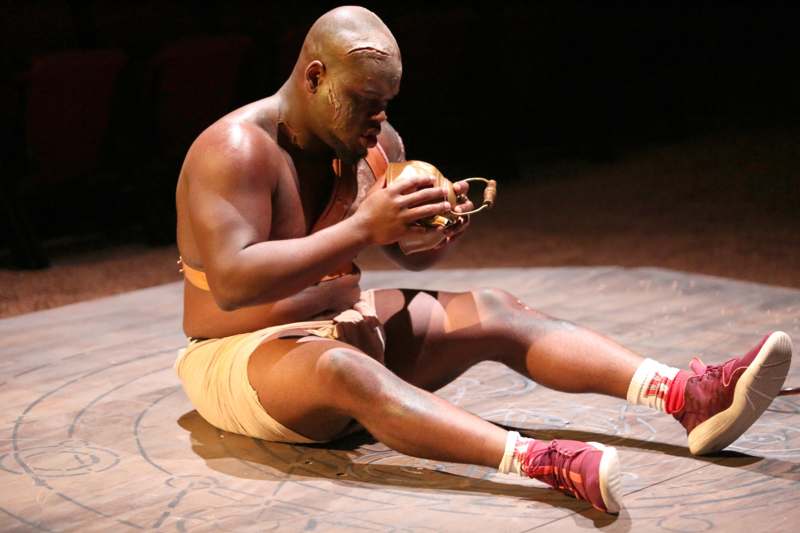 a man sitting on a stage holding a jug