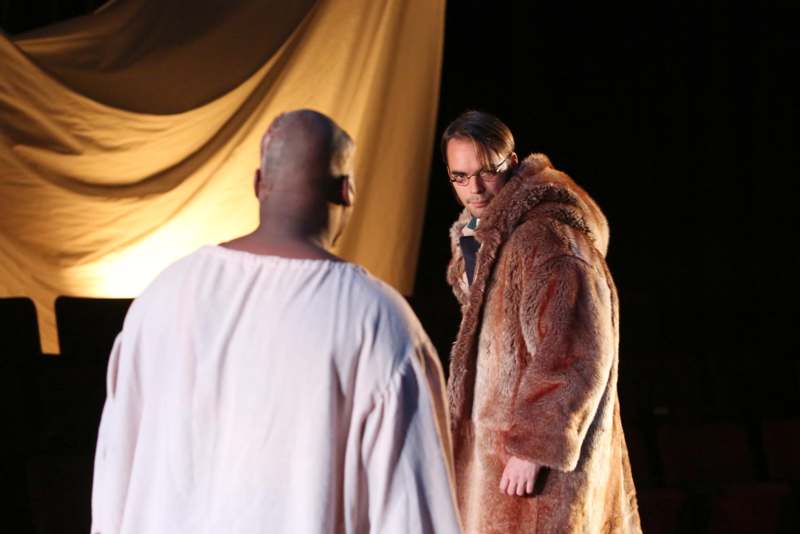 a man in a fur coat looking at another man in a robe