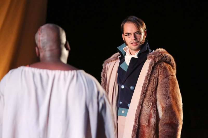 a man in a fur coat looking at another man in a white robe