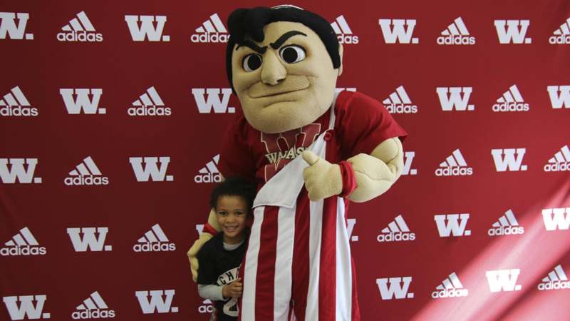 a person in a mascot garment holding a boy