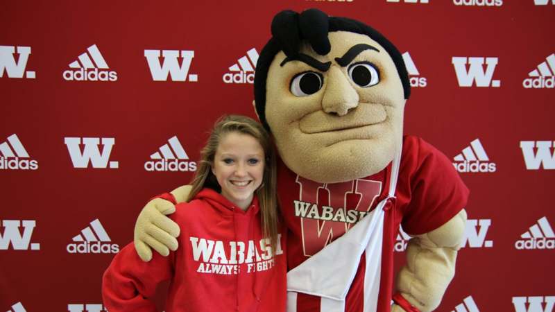 a woman posing with a mascot