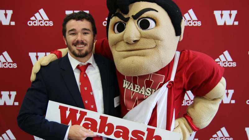a man in a suit and tie holding a mascot