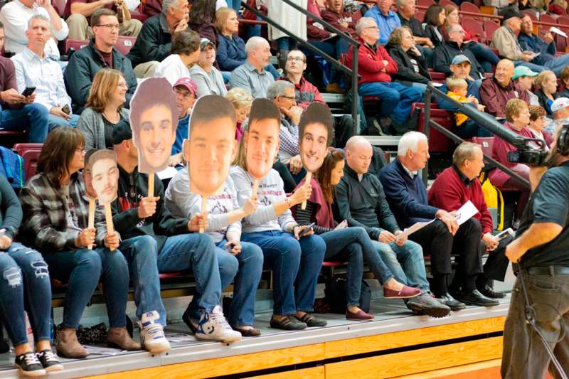 a group of people sitting in bleachers holding up cutouts of faces