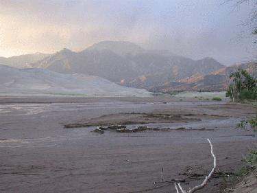 a dry river bed with mountains in the background