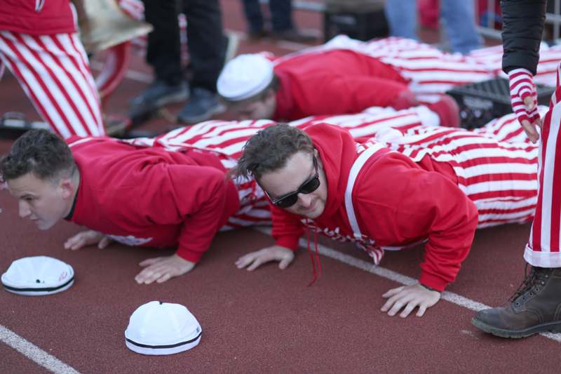 a group of people in red and white striped outfits on a track