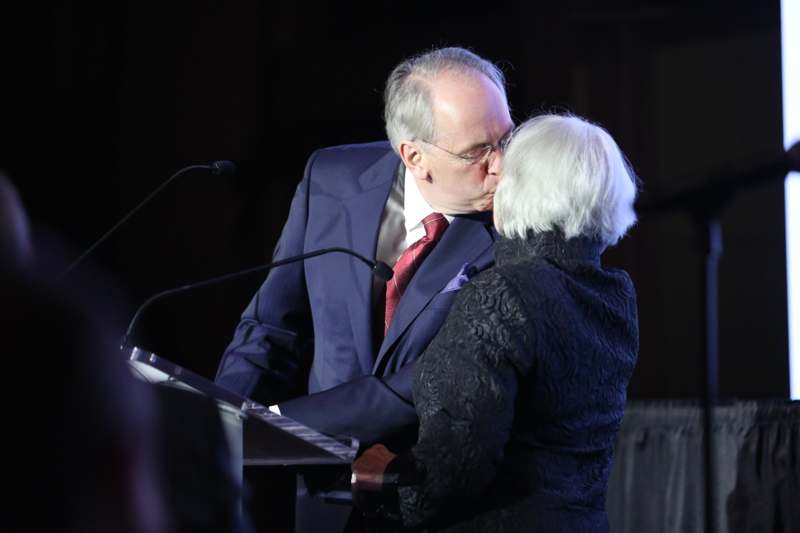 a man kissing a woman at a podium
