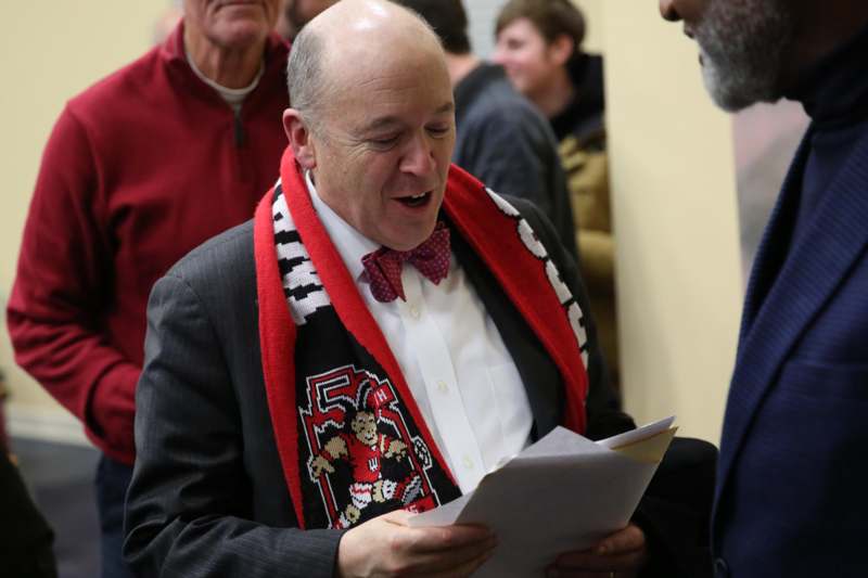 a man in a bow tie and a scarf reading a piece of paper