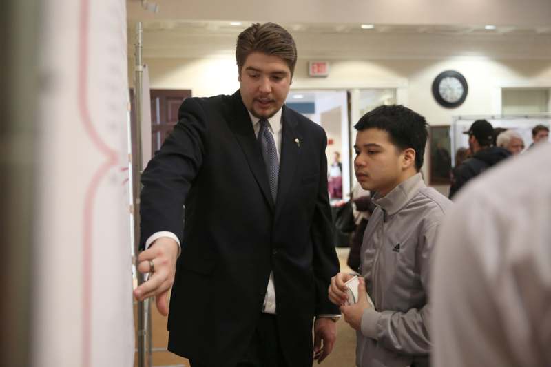 a man in a suit pointing at a whiteboard