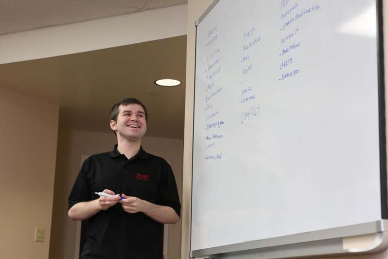 a man standing next to a whiteboard