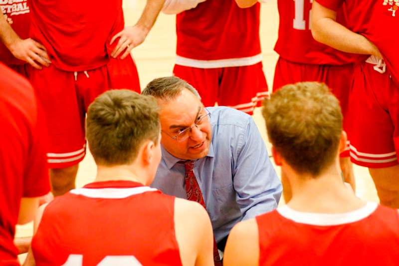 a man in a red tie talking to a basketball team