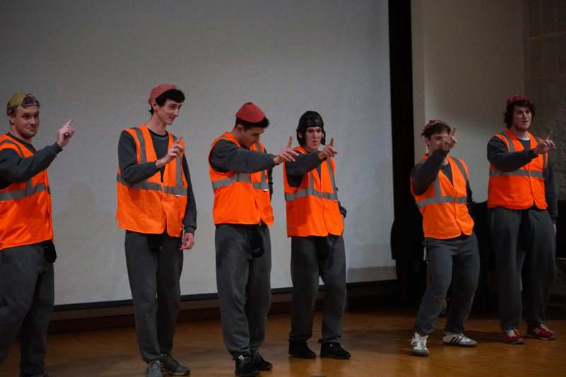 a group of men in orange vests and hats on a stage