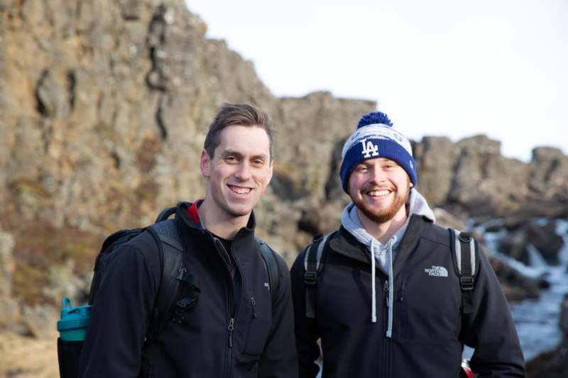 two men standing in front of a rocky cliff