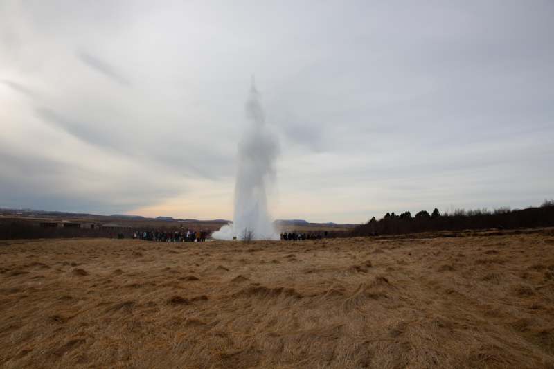 a group of people standing around a geyser