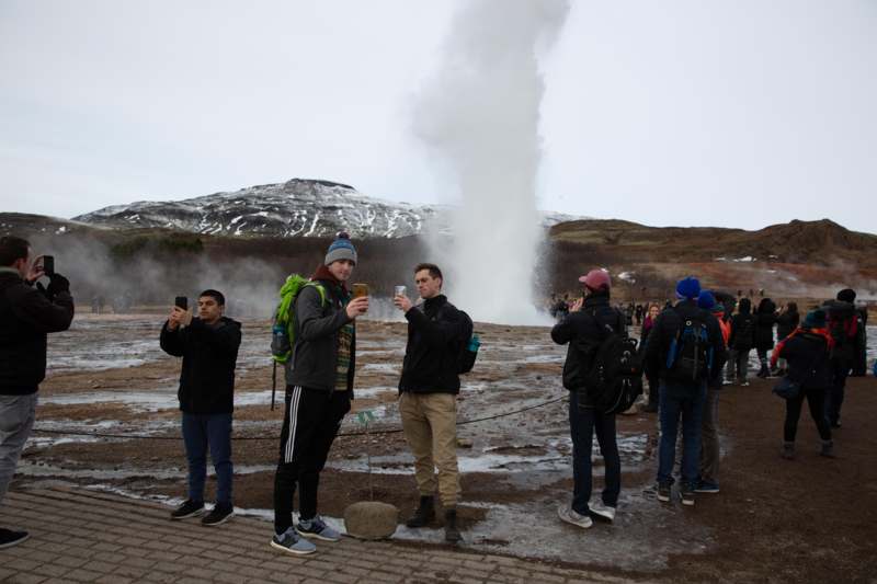 a group of people taking a picture of a geyser