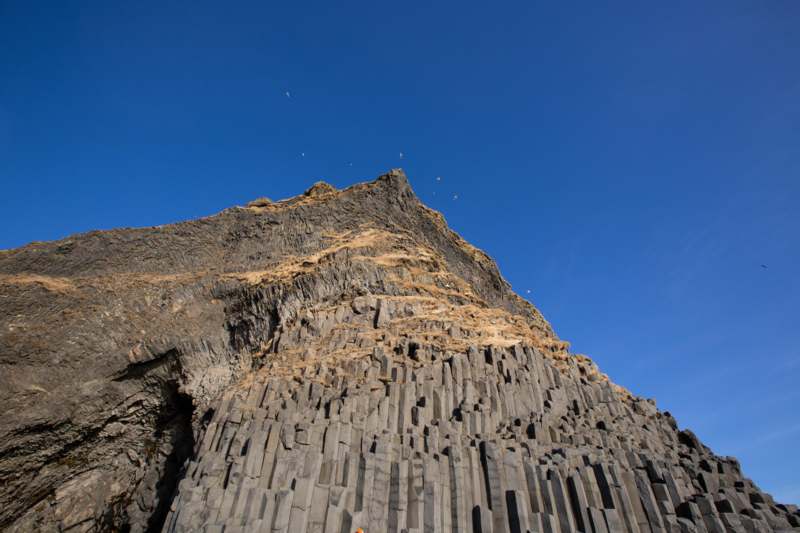 a rock cliff with birds flying in the sky