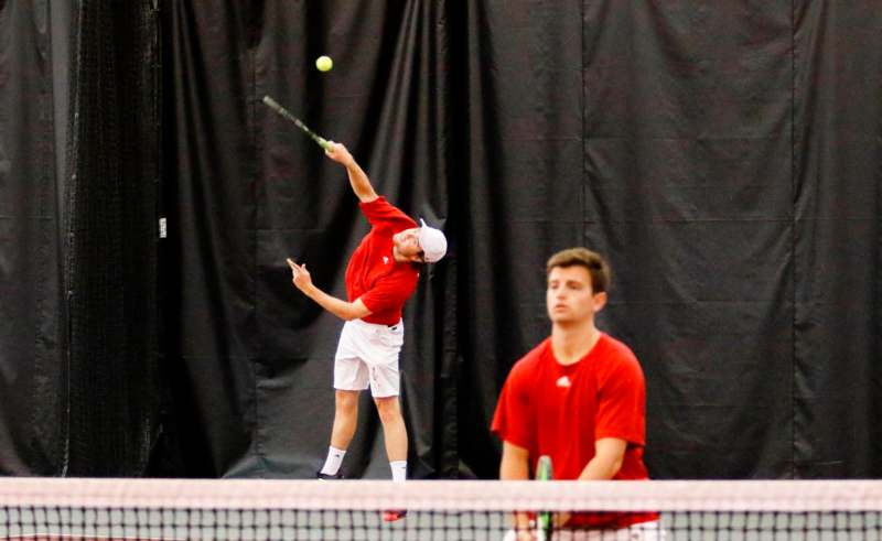 a man in red shirt hitting a tennis ball with a racket