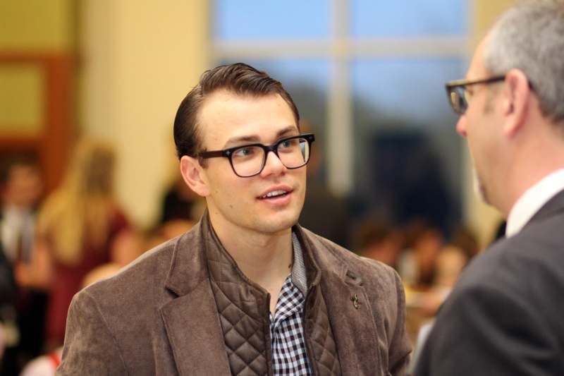 a man in glasses talking to another man
