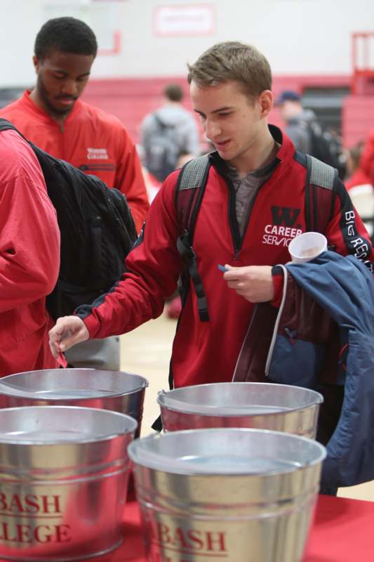 a man in red jacket standing next to buckets