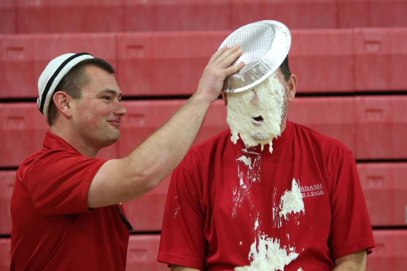 a man putting a pie on a man's face