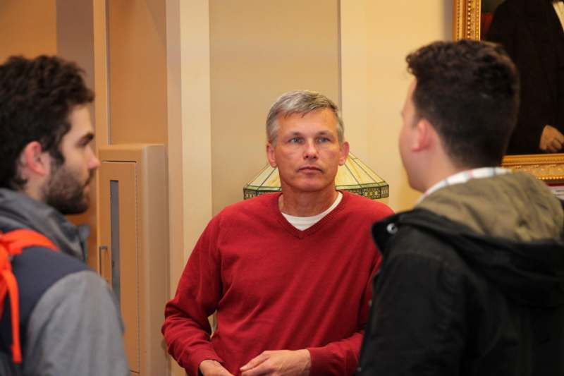a man in a red sweater talking to a group of men