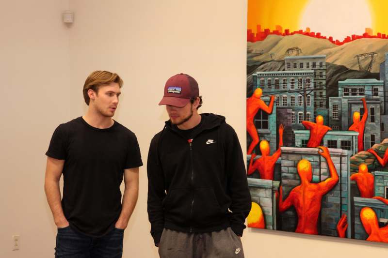 two men standing in front of a painting