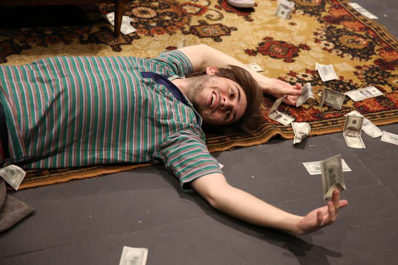a man lying on the floor with money on his head